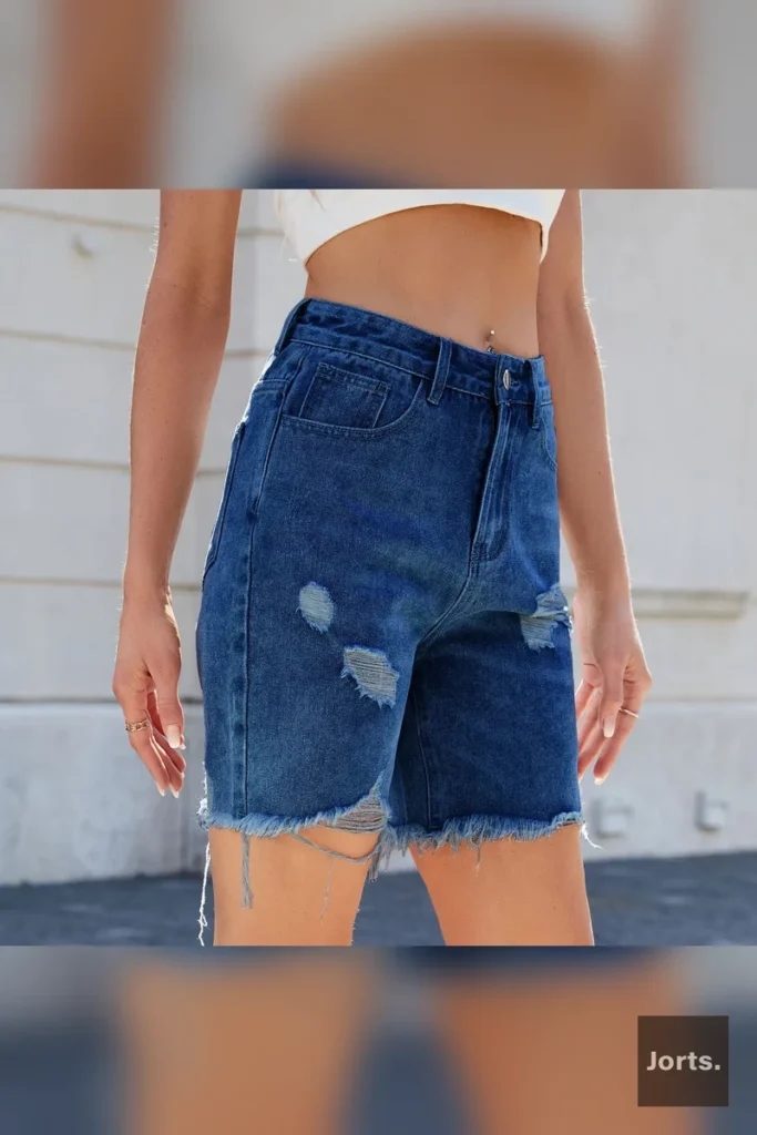 Close-up detail of the distressed rips and tears on the rayon fabric of the cropped jorts.