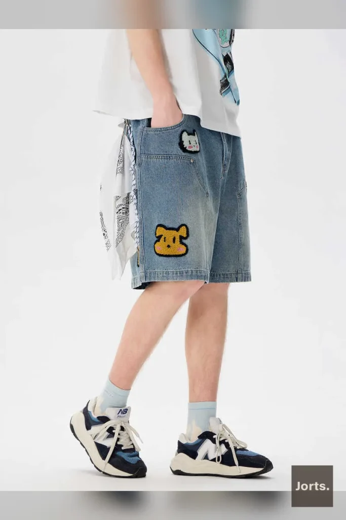 Side profile of men's baggy embroidered workwear denim shorts showing relaxed fit and washed fabric texture.