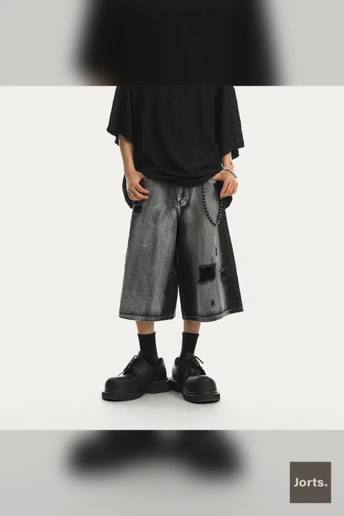 Mens distressed black denim jorts with a mid-rise and straight-leg fit, styled for Y2K streetwear.
