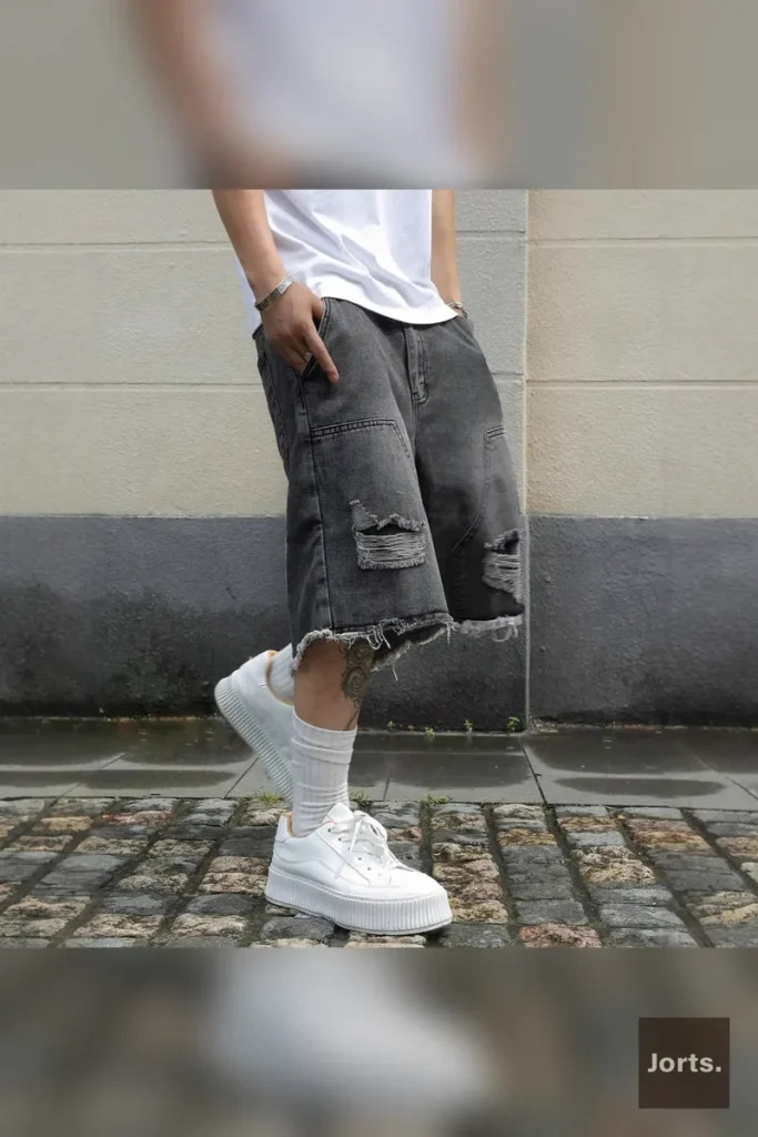 Model wearing mens gray straight-leg denim jorts as part of a Y2K streetwear outfit, styled for summer comfort and edgy look.